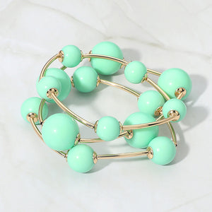 Mint beaded stackable stretch bracelet set on gold on white marble background