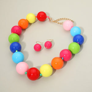Multi-Color chunky ball beaded statement necklace set with oversized round beads and matching earrings, displayed on a beige background.