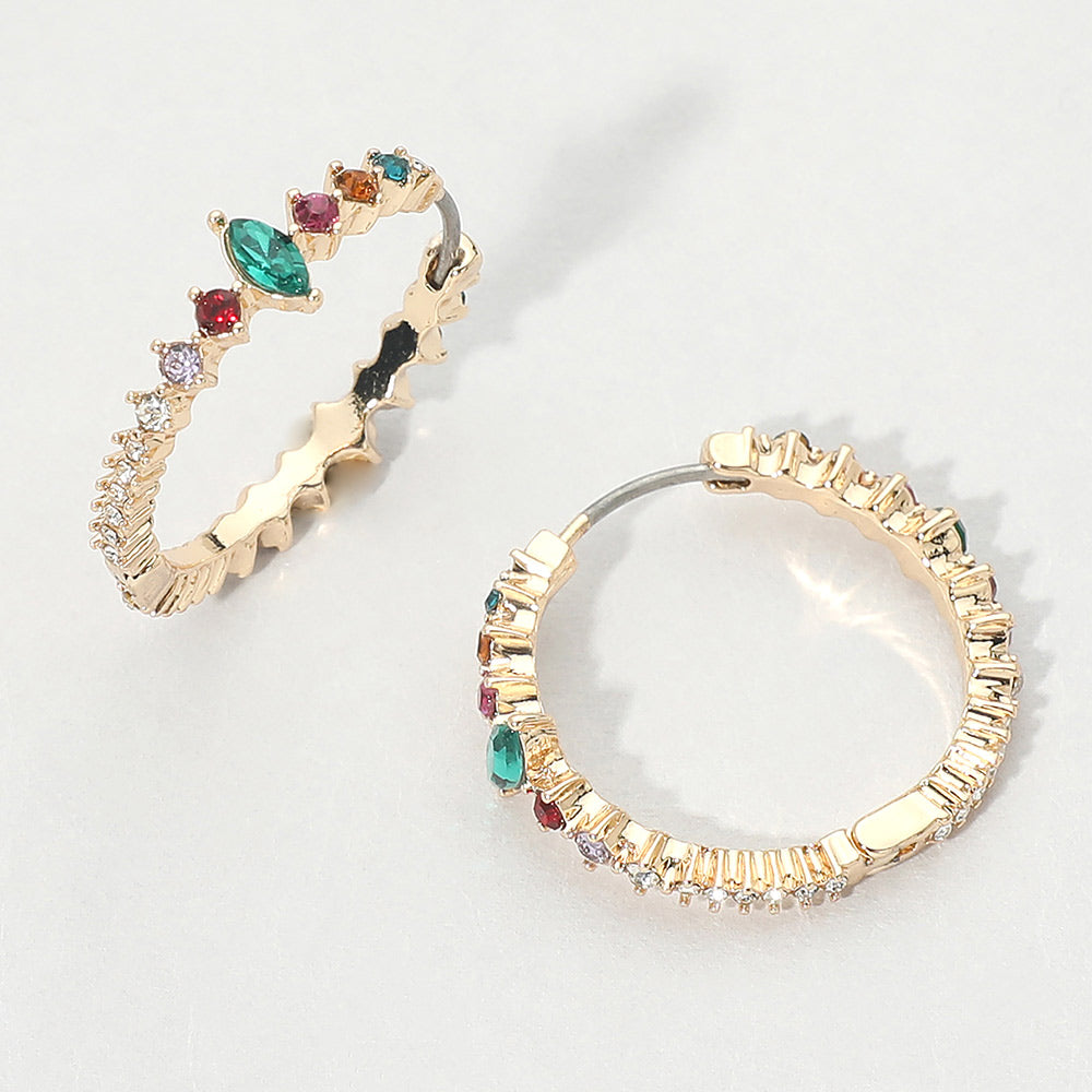 A pair of gold huggie hoop earrings with jewel tone multi-color marquise and round gemstones, displayed on a light gray background.