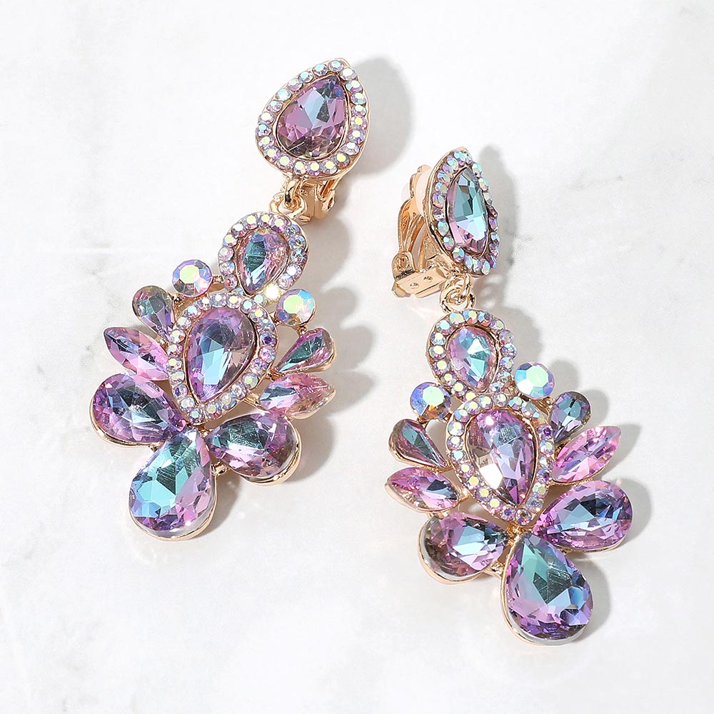 Gold-tone chandelier clip-on earrings with multi colors of purple and light blue teardrop and oval faceted crystals surrounded by smaller clear rhinestones, displayed on a white marble surface.