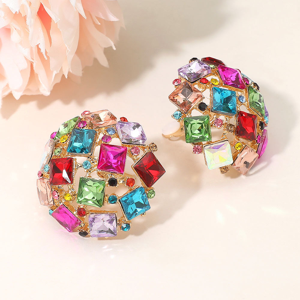 Multi-color square stone cluster dome clip-on earrings with a geometric rhinestone design and gold-tone setting on a light background with flowers
