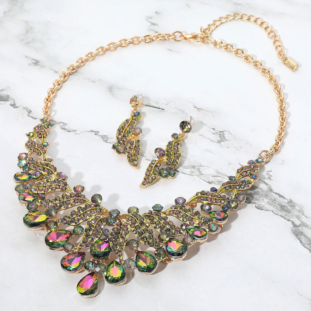 Multi-color teardrop leaf crystal collar necklace set on gold with matching earrings, bold statement jewelry for prom and evening wear on a marble background