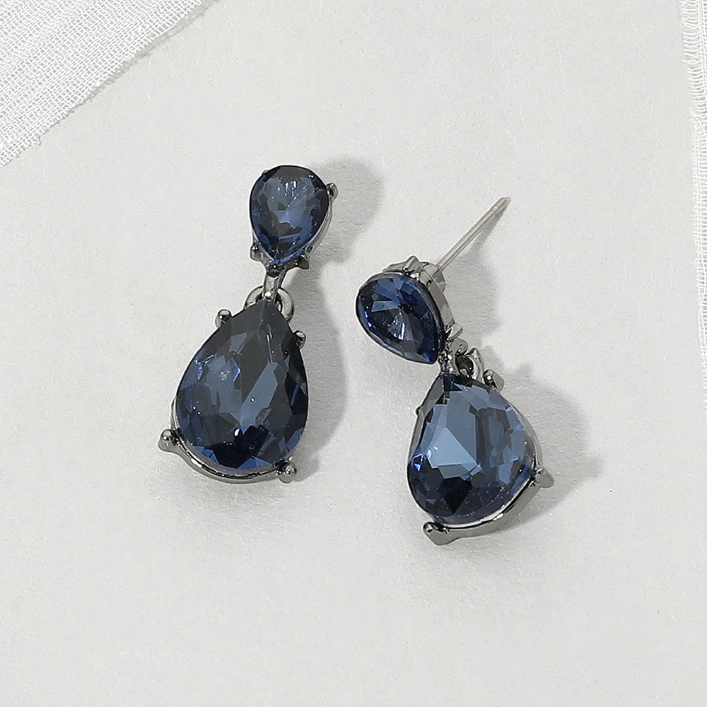 Double teardrop dangle earrings with navy blue crystals on gunmetal, featuring smaller faceted teardrops above larger teardrop drops, displayed on a white textured surface.