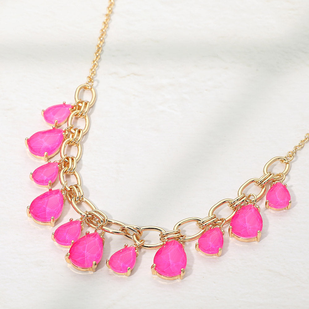 Neon fuchsia hot pink crystal teardrop statement necklace on gold on white background