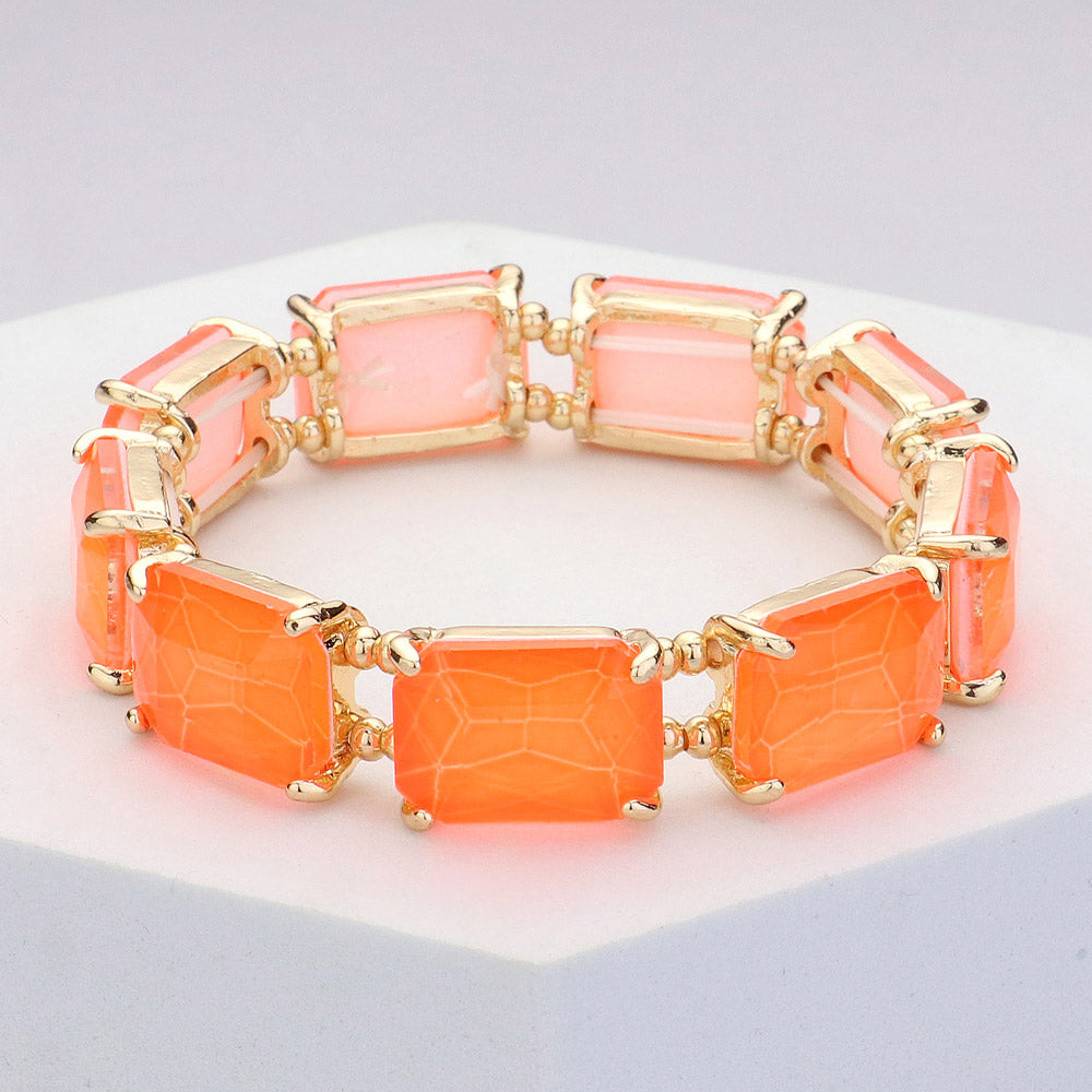 Bracelet with neon coral stones and gold accents on a white background
