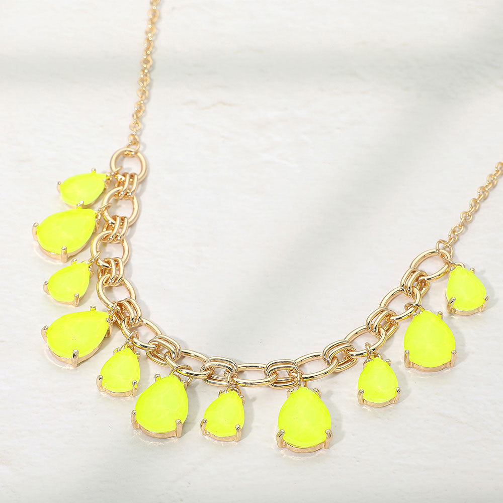 Neon yellow crystal teardrop statement necklace on gold on white background