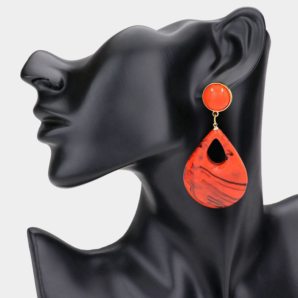 Orange resin teardrop cutout dangle earrings on a black mannequin ear on a white background— bold modern 3.25" fashion statement jewelry.