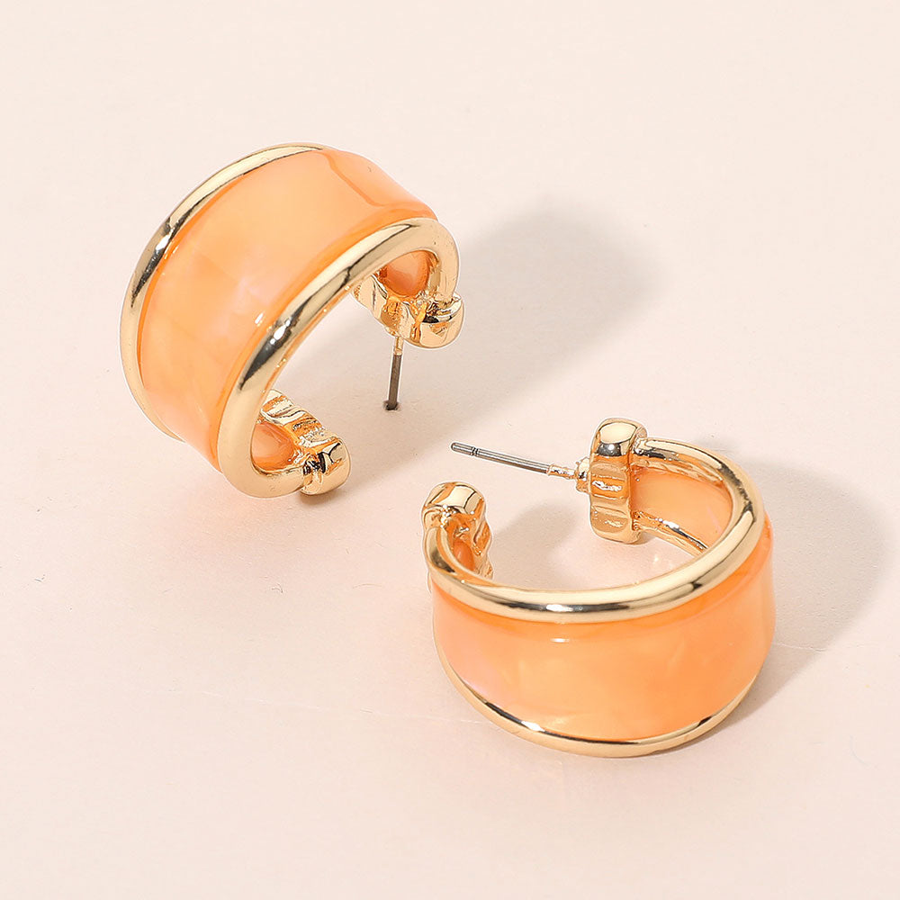 Orange marbled resin half hoop earrings with wide chunky statement design trimmed in gold for fun fashion and everyday wear on a light beige background