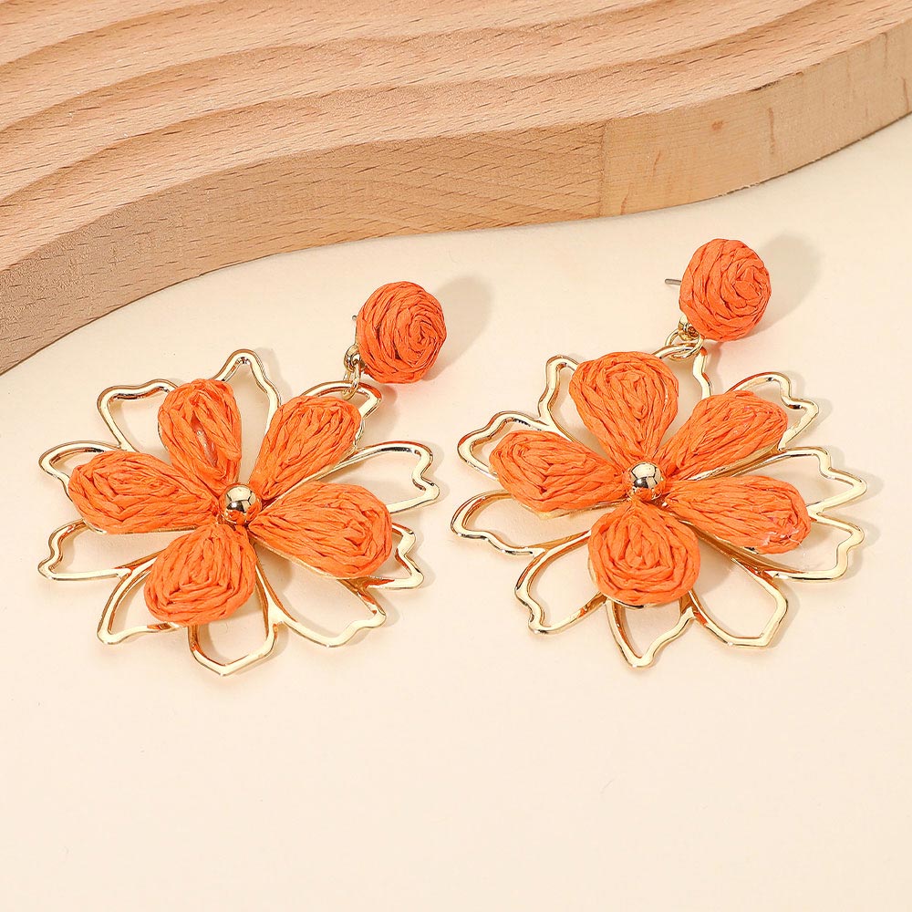 Orange raffia floral petal dangle earrings with boho statement style for runway, pageant outfit of choice, or everyday fashion with wooden background