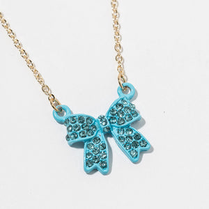 Close up of Bow pendant necklace with aqua crystals in an aqua setting on a gold-tone chain, measuring 15.5 inches with a 2-inch extender. The bow measures 0.75 inch wide by 0.75 inch long, with two rounded loops, a center knot, and two ribbon tails covered with small round crystals, displayed on a white background