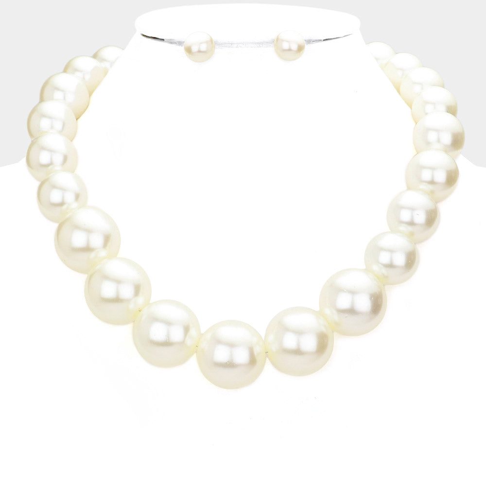Cream oversized pearl statement necklace set with large round pearl beads and matching earrings, displayed on a white mannequin bust.