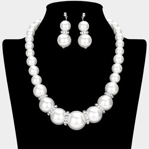 White oversized pearl and crystal statement necklace set with graduated round pearls, crystal accents between the pearls, and matching drop earrings, displayed on a black jewelry bust.