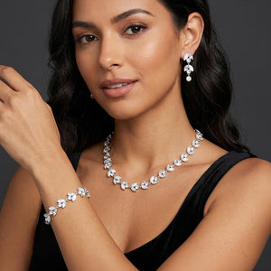 White pearl and crystal bridal jewelry set in a silver finish featuring a coordinating necklace, drop earrings, and bracelet with leaf-inspired accents, shown here on a model wearing the set. 