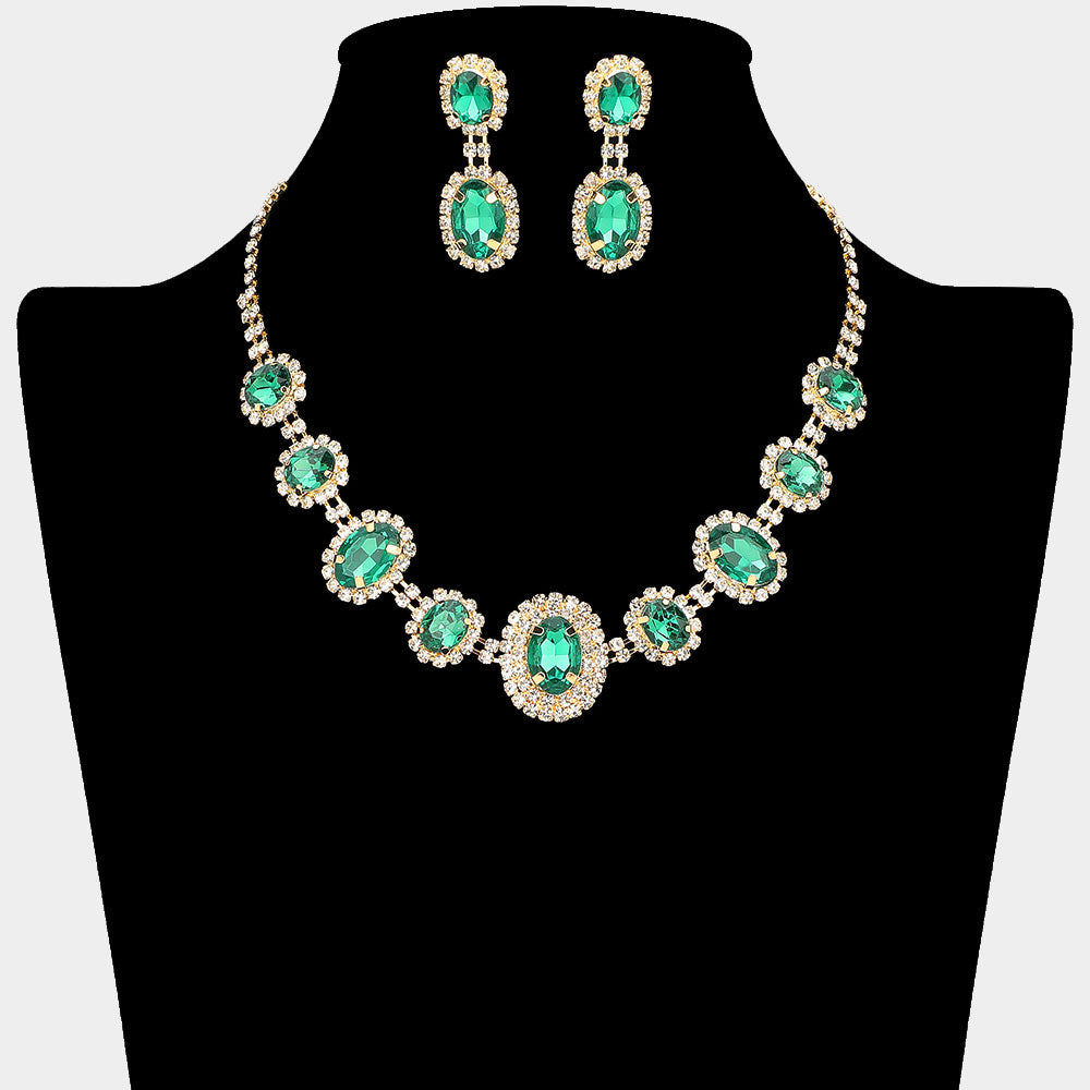 Jewelry set with emerald green gemstones surrounded by a halo of rhinestones on gold backing shown on a black mannequin bust.