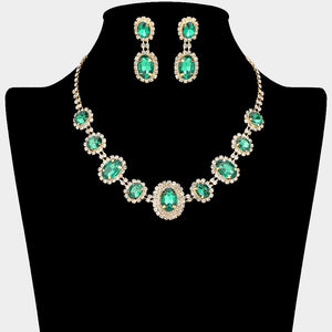 Jewelry set with emerald green gemstones surrounded by a halo of rhinestones on gold backing shown on a black mannequin bust.
