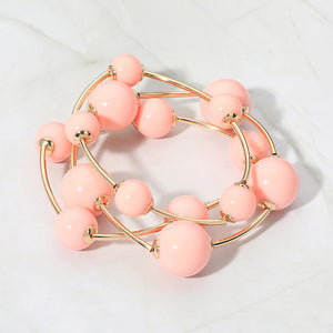Peach beaded stackable stretch bracelet set on gold on white marble background