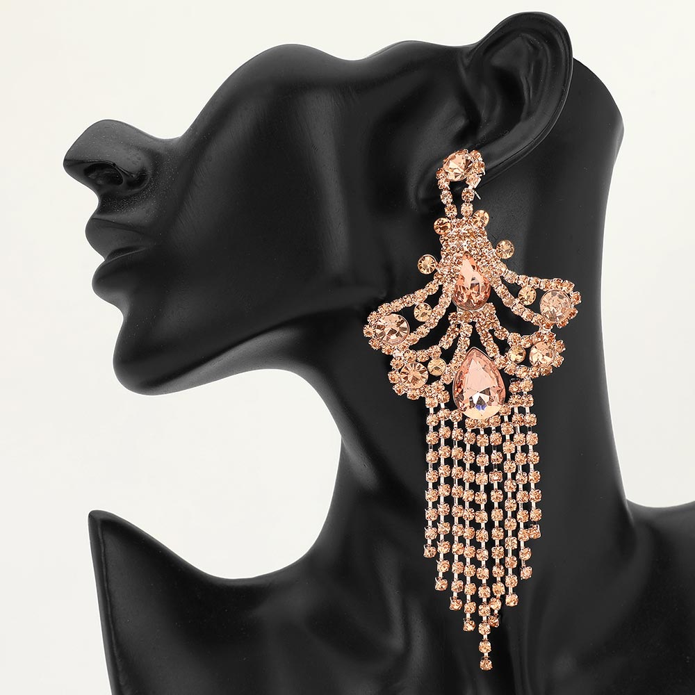 A large ornate Peach crystal statement earring on gold with cascading bead fringe and clear crystal accents on a black earring mannequin.