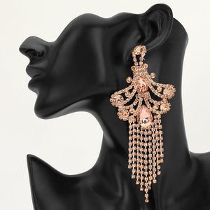 A large ornate Peach crystal statement earring on gold with cascading bead fringe and clear crystal accents on a black earring mannequin.