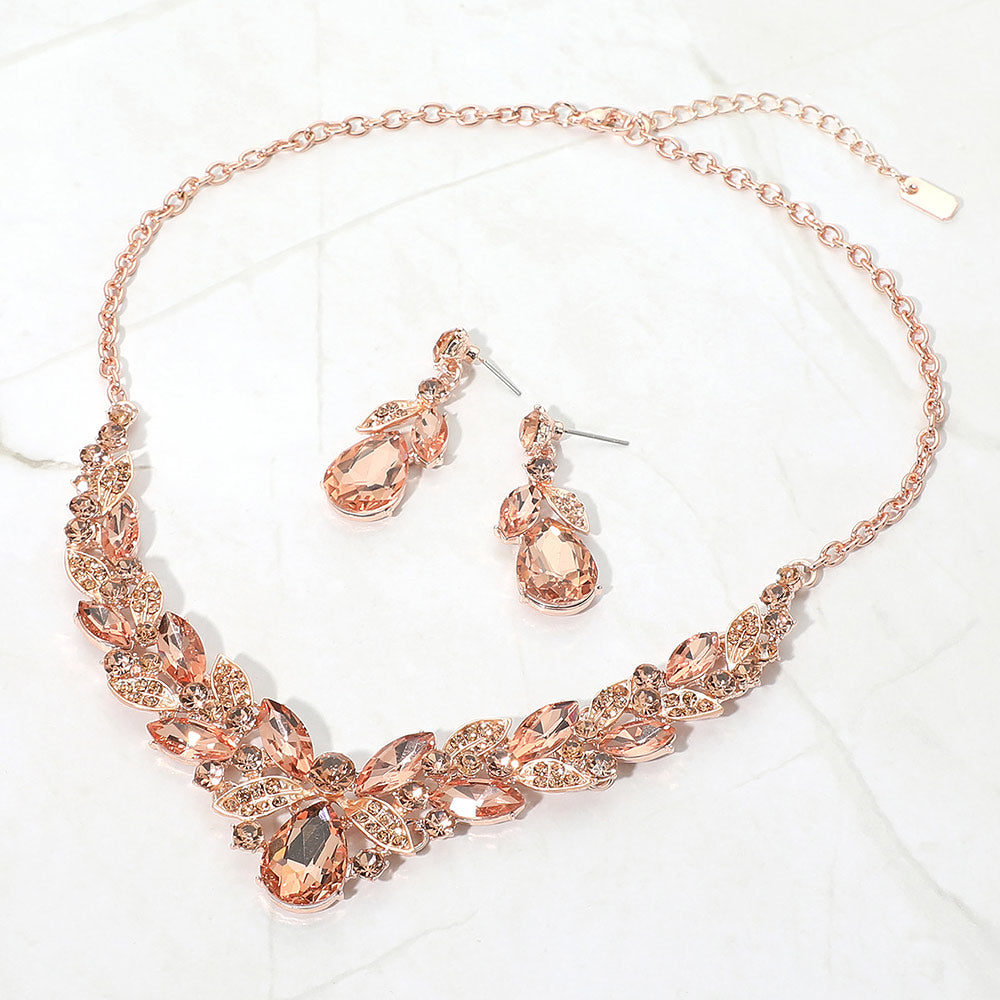 Peach teardrop and marquise crystal jewelry set on rose gold displayed on white marble background