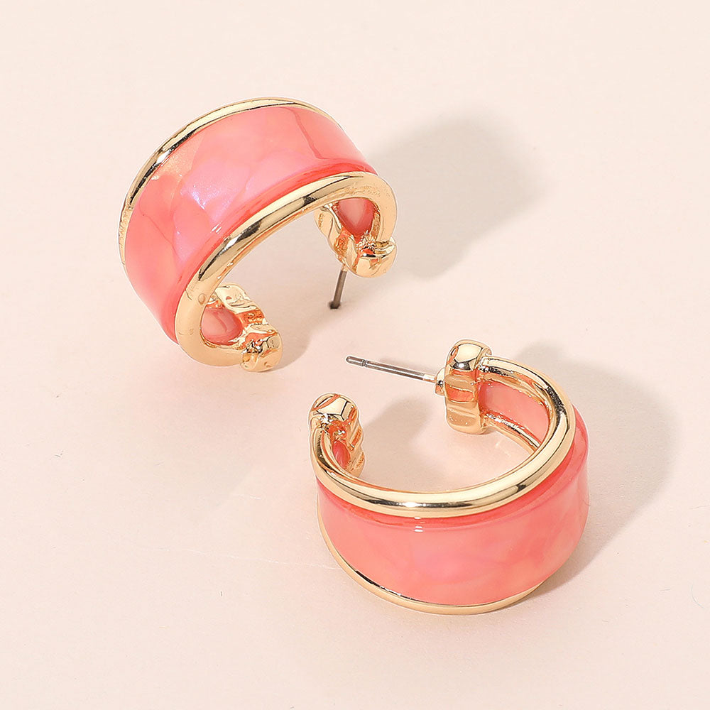 Pink marbled resin half hoop earrings with wide chunky statement design trimmed in gold for fun fashion and everyday wear on a light beige background