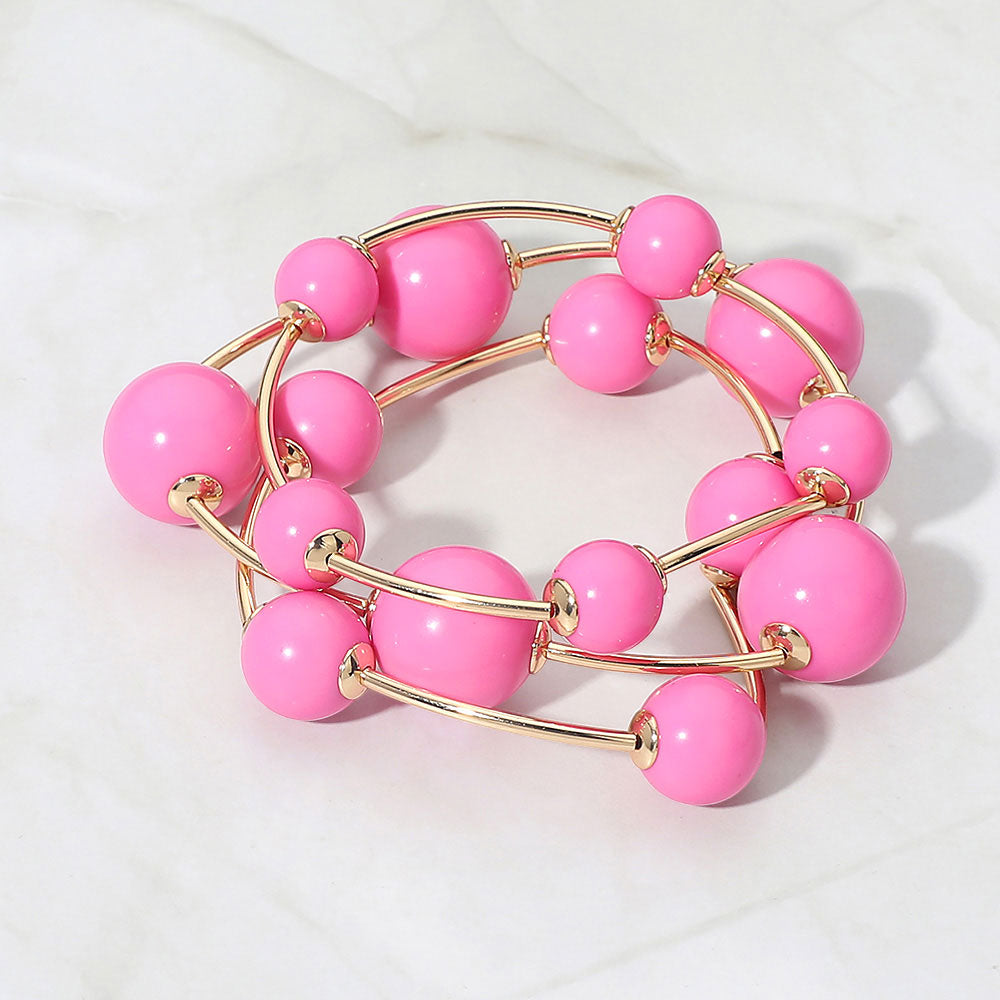 Pink beaded stackable stretch bracelet set on gold on white marble background