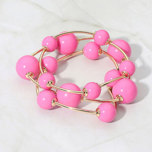 Pink beaded stackable stretch bracelet set on gold on white marble background