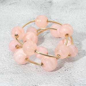 Pink chunky ball 3-piece stretch bracelet set on gold displayed on a light textured background.