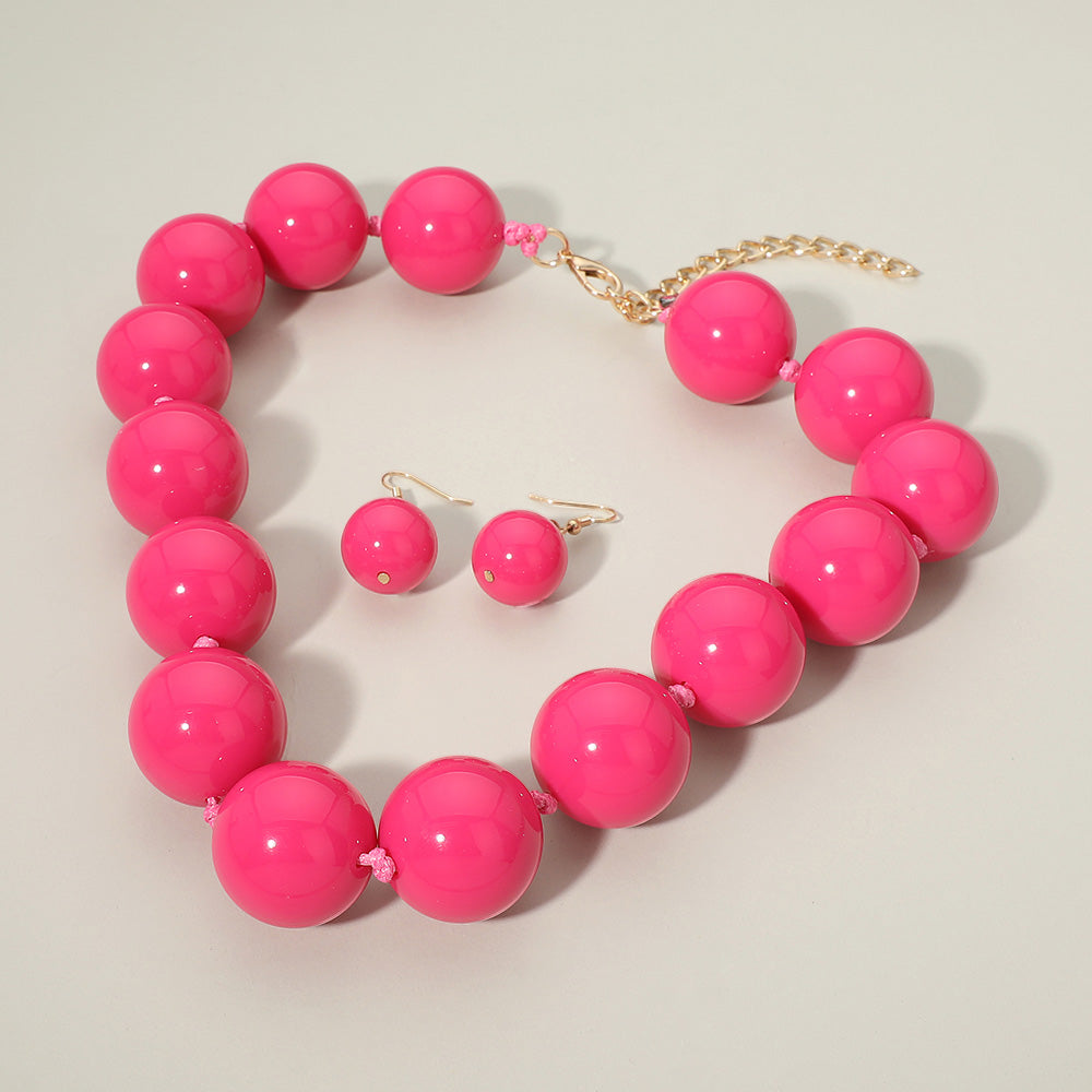 Hot Pink chunky ball beaded statement necklace set with oversized round beads and matching drop earrings, displayed on a light cream background.