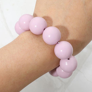 Pink chunky ball beaded stretch bracelet with oversized round beads worn on a woman's wrist.