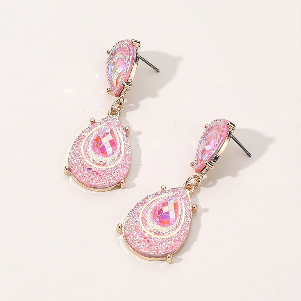 Pink crystal glitter teardrop drop earrings on gold on light beige background