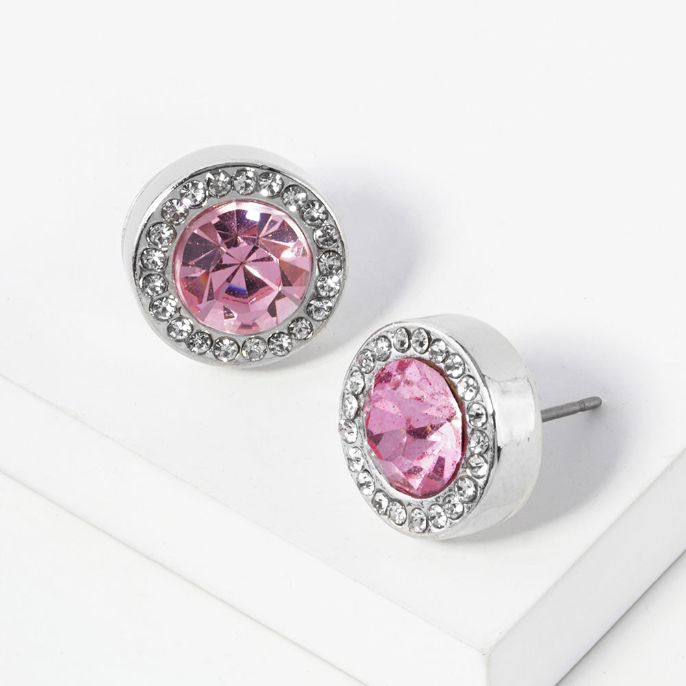 A pair of silver stud earrings with an oval pink faceted center stone surrounded by a halo of small clear rhinestones, displayed on a clean white surface.