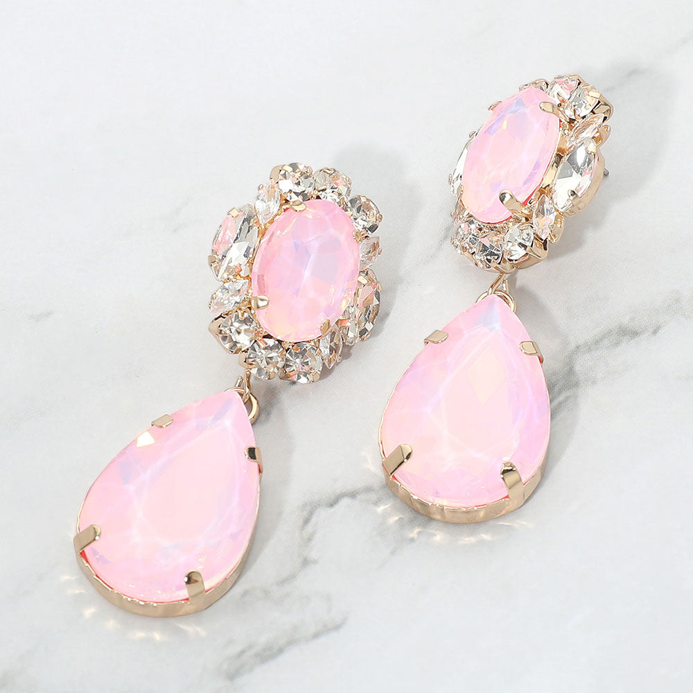 Pink oval and teardrop dangle earrings on gold on a white marble background