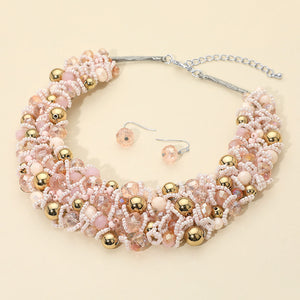 Pink faceted beaded collar necklace set with matching earrings in a fun fashion statement style on a beige background