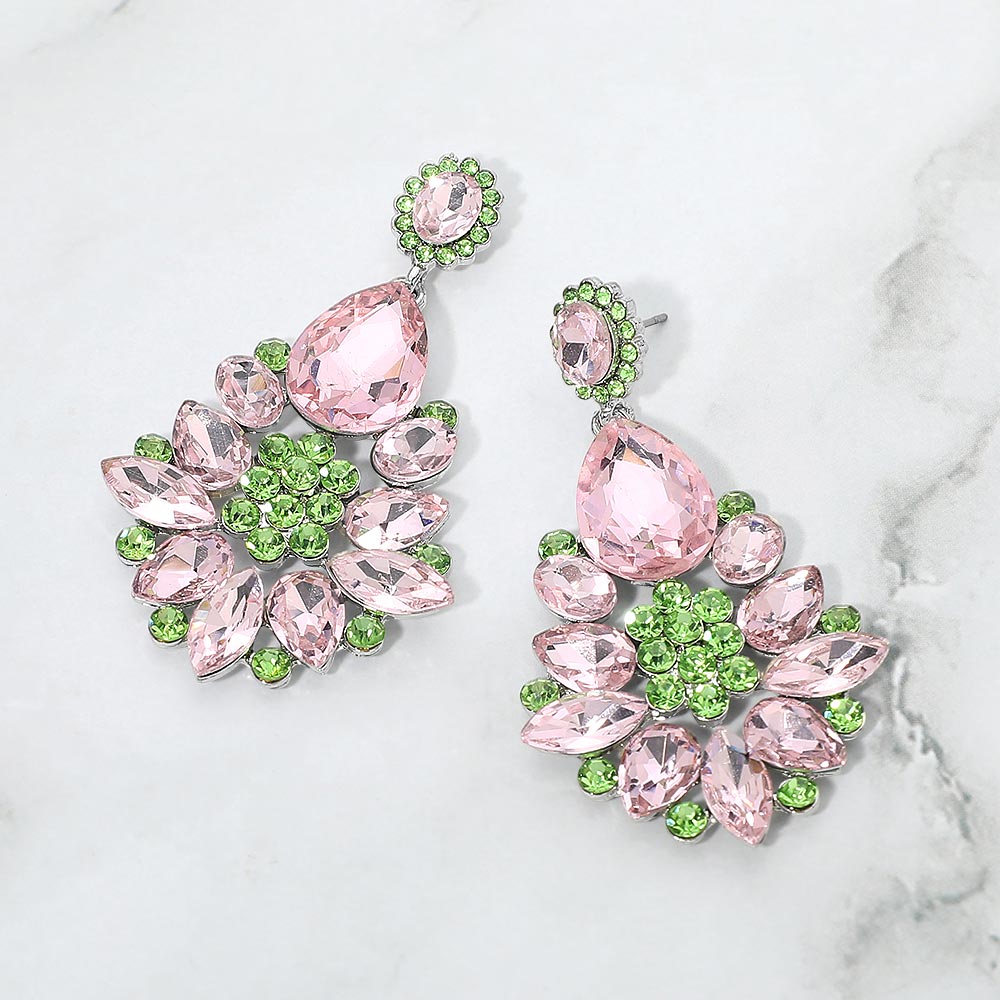Floral teardrop earrings with pink and green crystals on silver, featuring oval crystal tops, large teardrops, and flower clusters with petal-shaped stones, displayed on white marble.