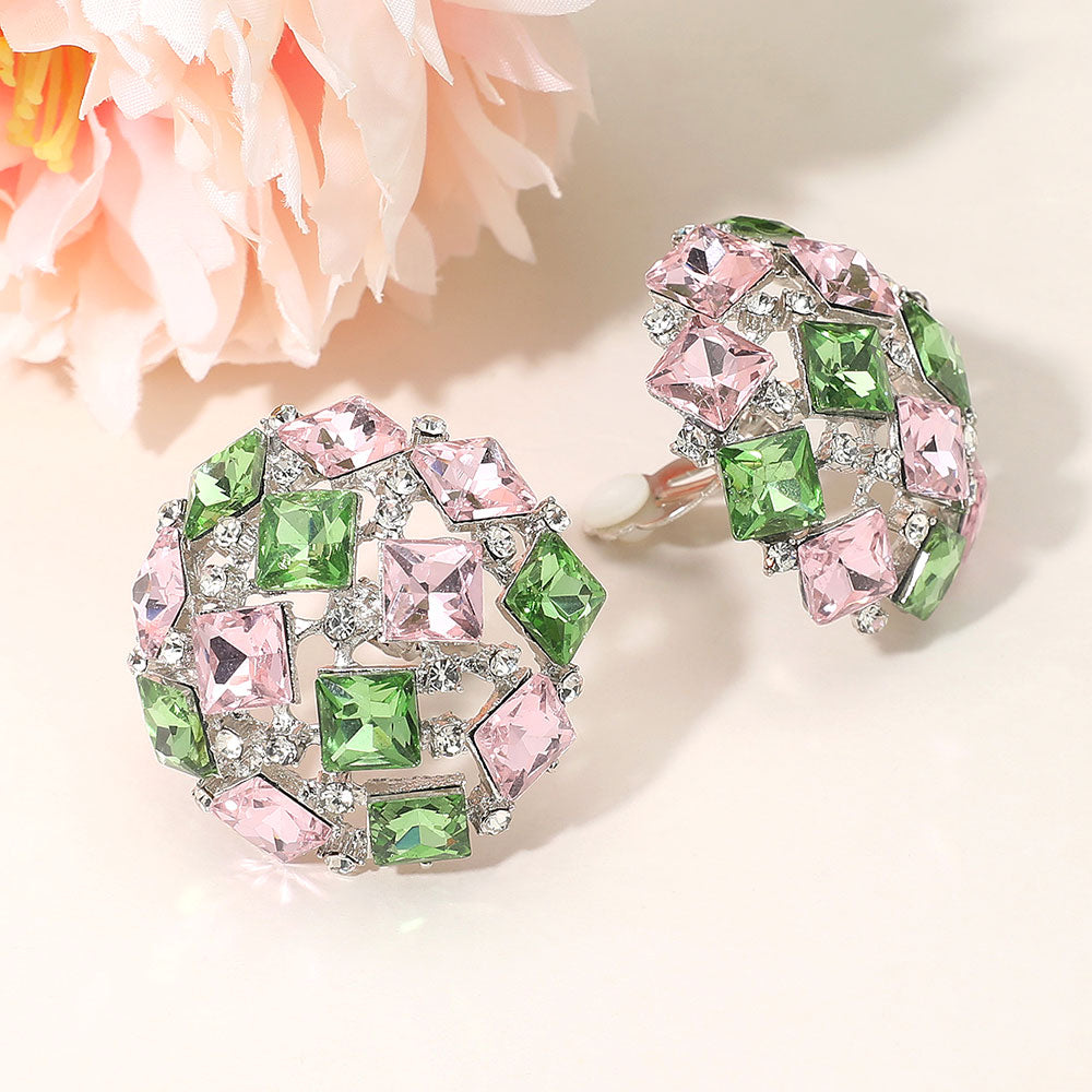 Pink and green square stone cluster dome clip-on earrings with a geometric rhinestone design and silver-tone setting on a light background with flowers