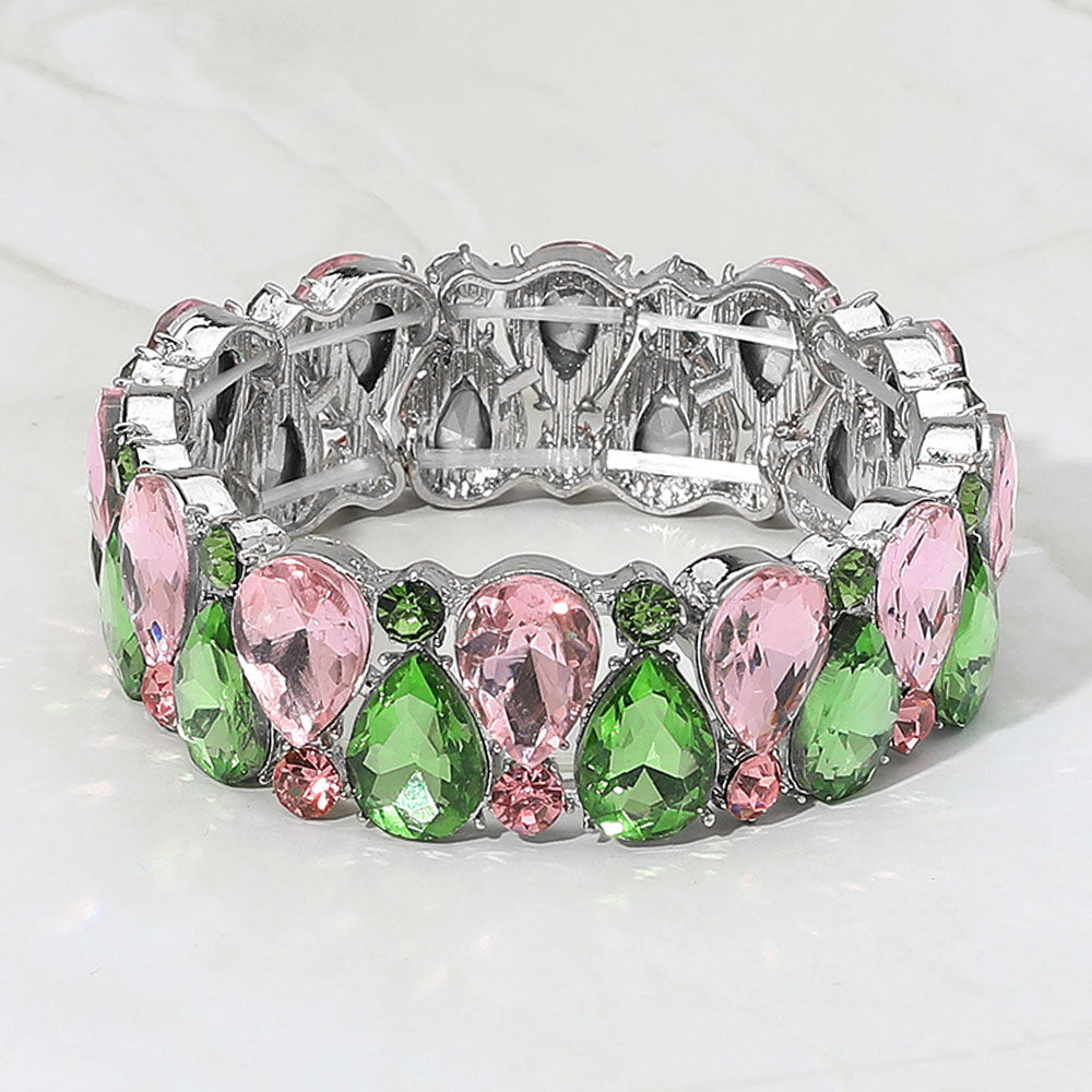 Pink and green teardrop and round stone cluster stretch bracelet on silver on white marble background
