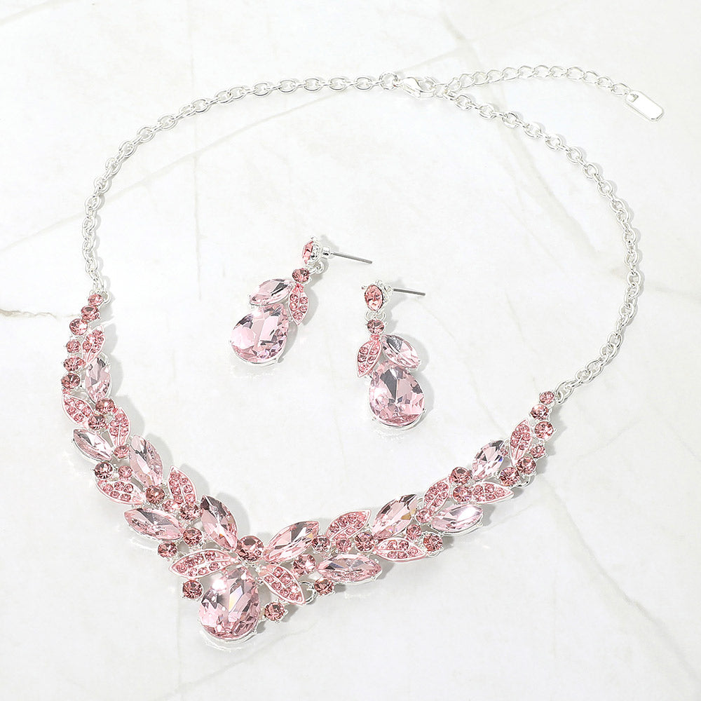 Pink teardrop and marquise crystal jewelry set on silver displayed on white marble background