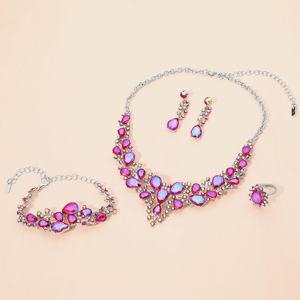 Fuchsia with reflective purple crystal 4-piece jewelry set on silver with statement necklace, matching bracelet, drop earrings and adjustable ring arranged on a light beige background.