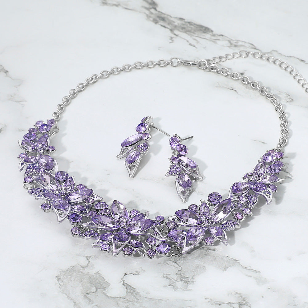 Purple stone collar-bib necklace set with earrings for homecoming, proms, or pageant events on a grey and white granite background