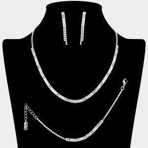 Clear crystal tennis-style jewelry set on silver-tone metal, featuring a single-row necklace, matching bracelet, and slender straight dangle earrings. Necklace measures 16 inches plus a 4-inch extender, bracelet 7 inches plus a 2-inch extender, and earrings 1.75 inches long. Arranged on a black jewelry bust against a light gray background.