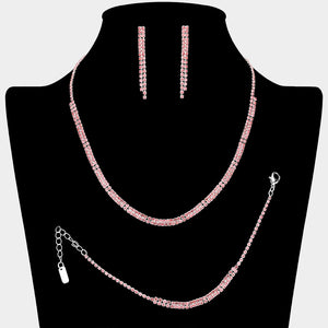 Pink crystal tennis-style jewelry set on silver-tone metal, featuring a single-row necklace, matching bracelet, and slender straight dangle earrings. Necklace measures 16 inches plus a 4-inch extender, bracelet 7 inches plus a 2-inch extender, and earrings 1.75 inches long. Arranged on a black jewelry bust against a light gray background.