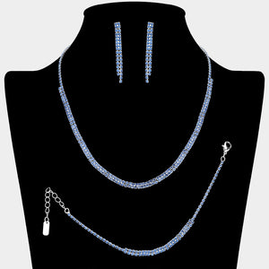 Light blue crystal tennis-style jewelry set on silver-tone metal, featuring a single-row necklace, matching bracelet, and slender straight dangle earrings. Necklace measures 16 inches plus a 4-inch extender, bracelet 7 inches plus a 2-inch extender, and earrings 1.75 inches long. Arranged on a black jewelry bust against a light gray background.