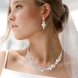 Clear rhinestone leaf cluster necklace set with teardrop crystal earrings, silver backed, for prom and evening wear shown on a pretty lady with a white blurred background. 