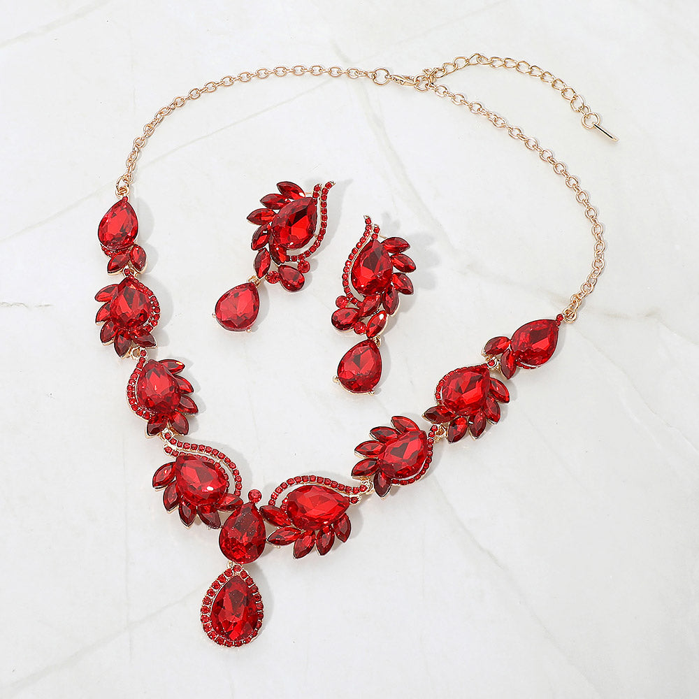 Red teardrop formal necklace and matching earrings set on gold displayed on a white background.