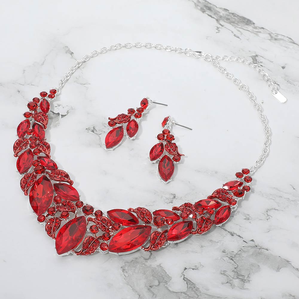 Red marquise leaf crystal necklace set on silver with matching earrings, bold statement jewelry for prom and evening wear on a marble background