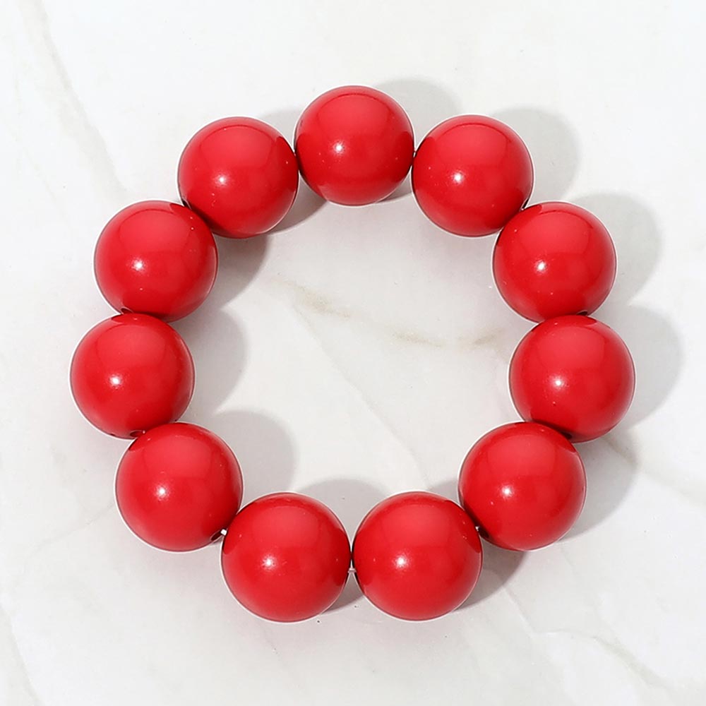 Red chunky ball beaded stretch bracelet with oversized round beads, displayed on a white marble background.