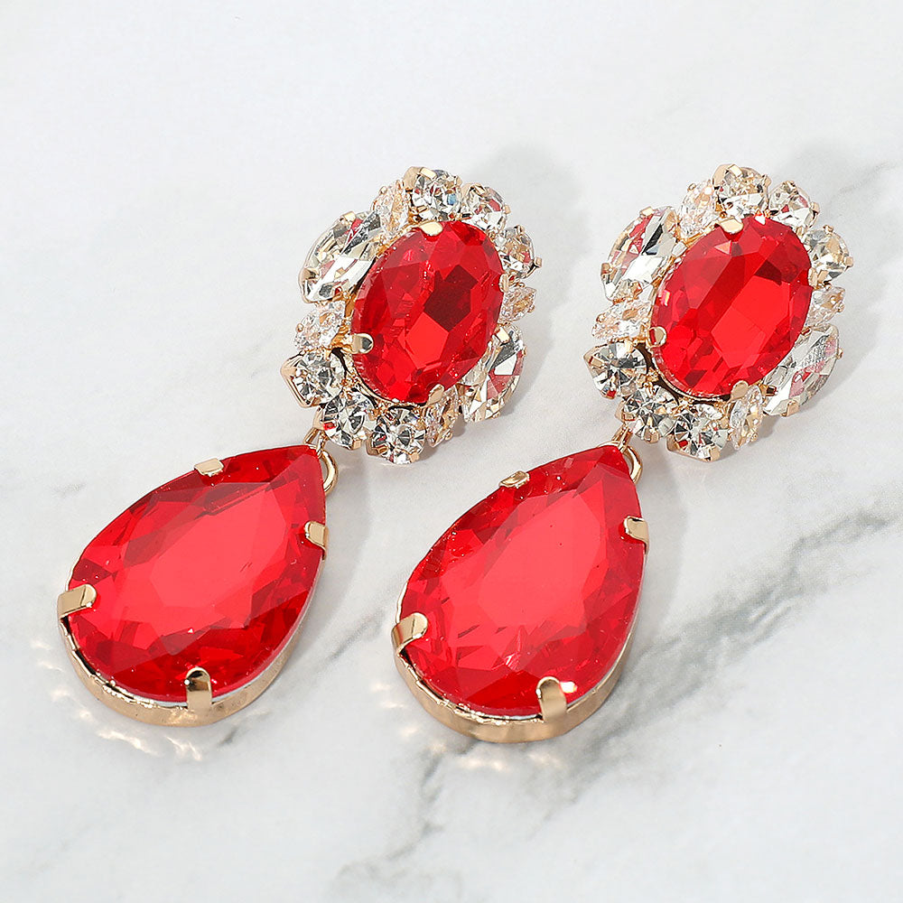 Red oval and teardrop dangle earrings on gold on a white marble background