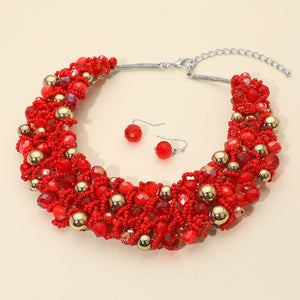 Red faceted beaded collar necklace set with matching earrings in a bold fun fashion statement design on a beige background