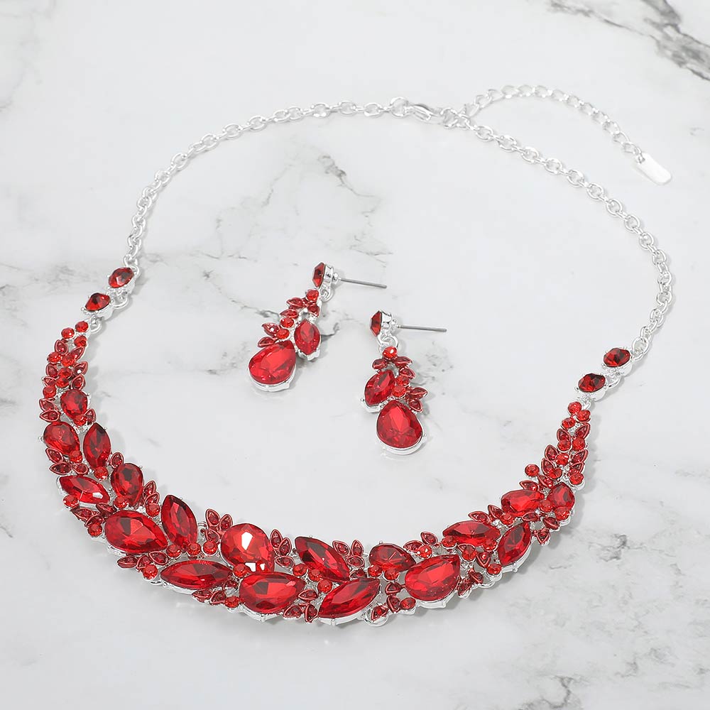 Red marquise crystal cluster necklace set on silver with matching earrings, elegant statement jewelry for prom and evening wear on a marble background