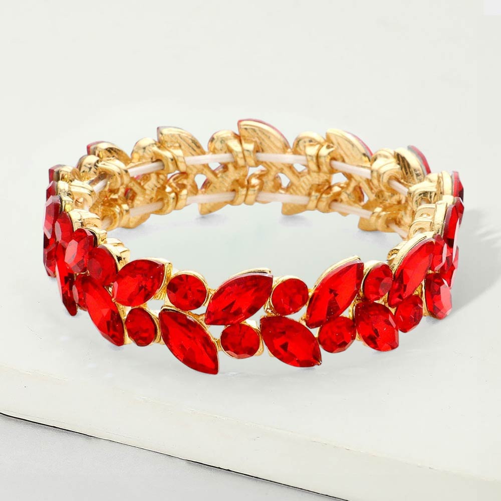 Red marquise and round stone cluster stretch bracelet on gold on a white marble background